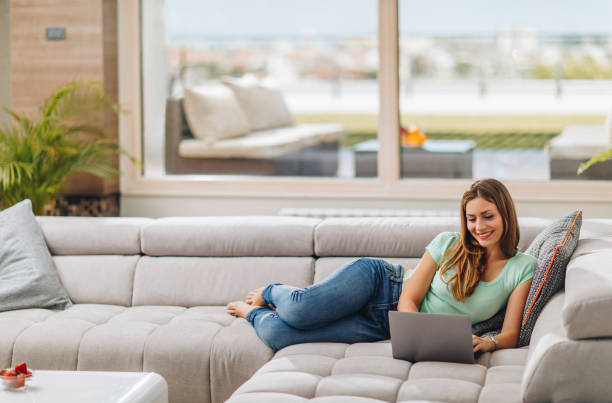 istock Young happy woman relaxing while using laptop in the living room. 938976048