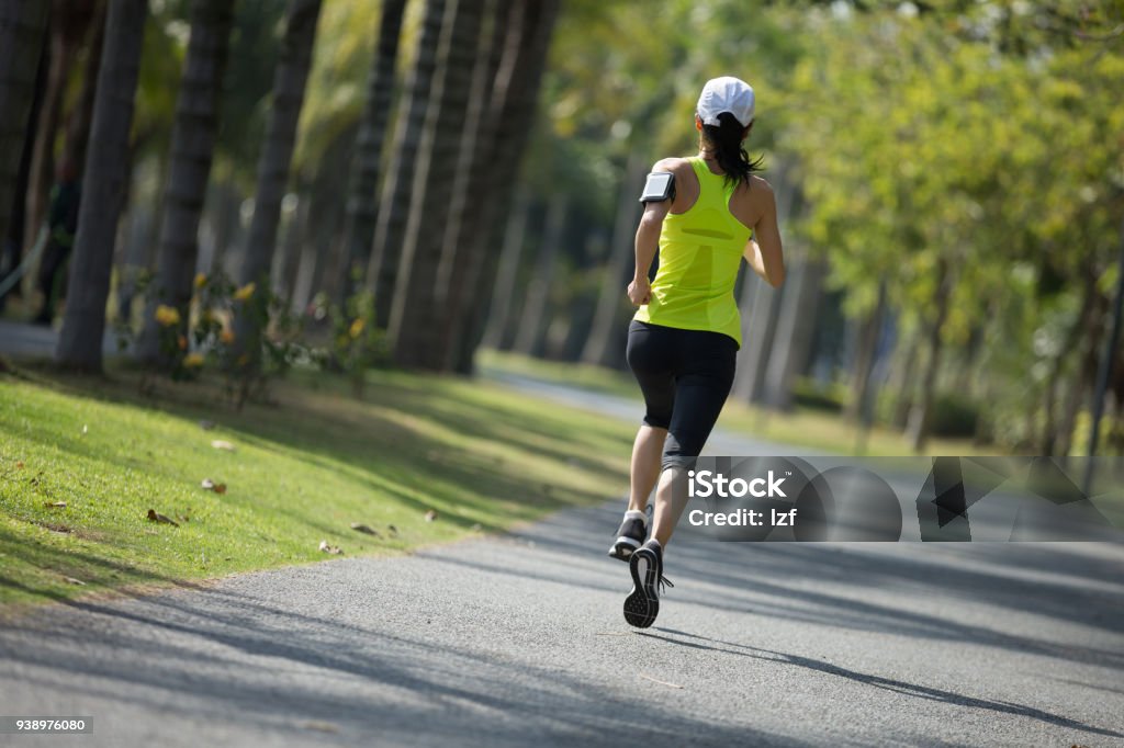 sporty young fitness woman running at tropical park Activity Stock Photo