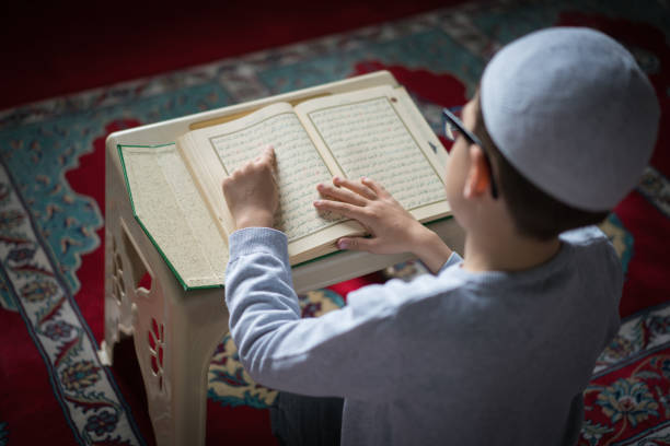 garçon musulman, lire le coran dans la mosquée - coran photos et images de collection