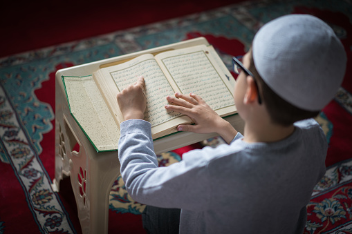 Muslim boy reading The Holy Koran in Mosque