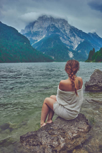 Lady at the lake Red head lady sitting at a beautiful italian lake in a white robe.Red head lady sitting at a beautiful italian lake in a white robe. back shoulder tattoos for women pictures stock pictures, royalty-free photos & images