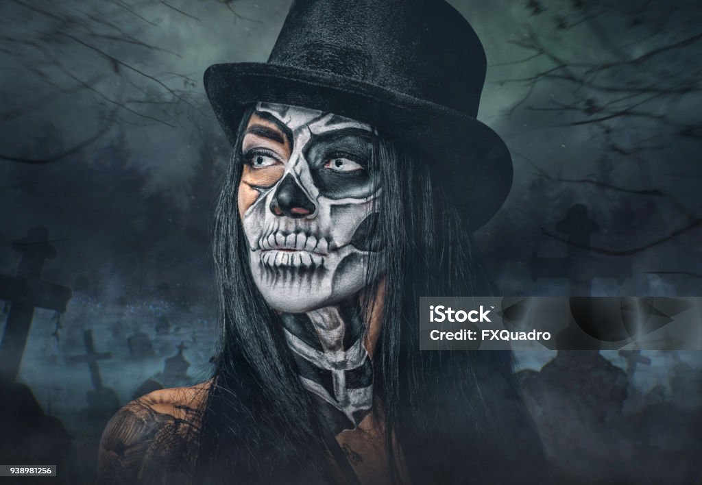 A woman with painted skull face. Portrait of female with skull make up in top hat on Halloween. Top Hat Stock Photo