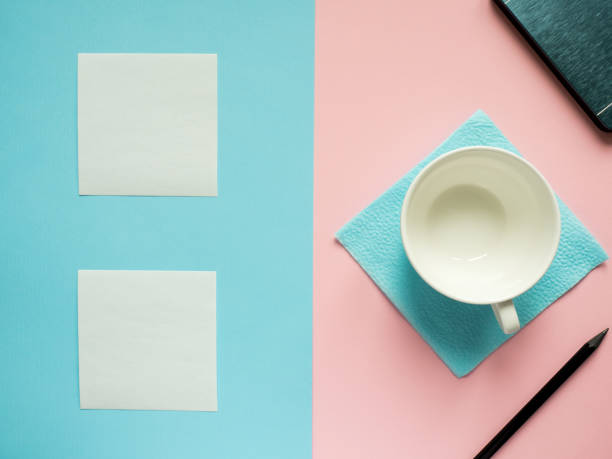 istock Business flat lay with copy space on a background divided in half pink and blue Notebooks to write text stickers Empty white Cup 938996142
