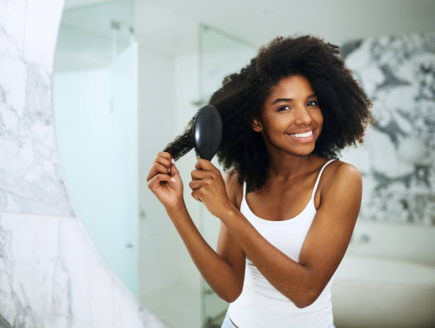 Taking care of her crown Portrait of an attractive young woman brushing her hair at home combing photos stock pictures, royalty-free photos & images