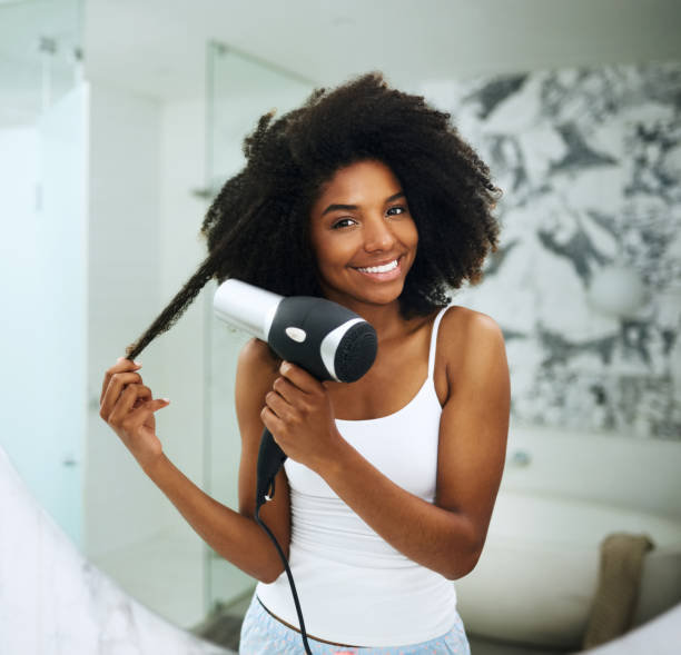 Beautiful hair requires proper care Portrait of an attractive young woman blowdrying her hair at home blow drying stock pictures, royalty-free photos & images