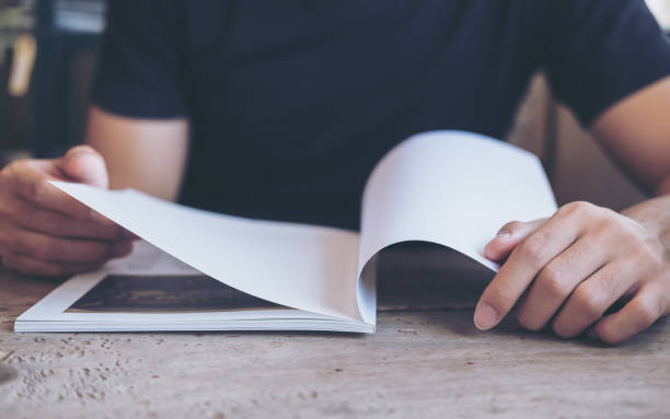 un hombre abrir y leer un libro de madera mesa de café vintage - intend fotografías e imágenes de stock