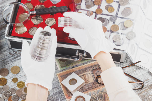 istock Hands in the white gloves with different collector coins in the boxes 938999616