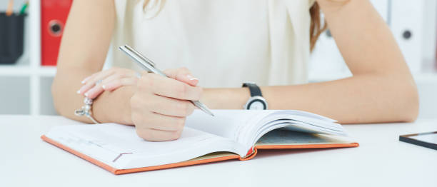 istock Female hands holding a silver pen closeup. Businesswoman making notes at office workplace. success, certified public accountant concept. 939006480