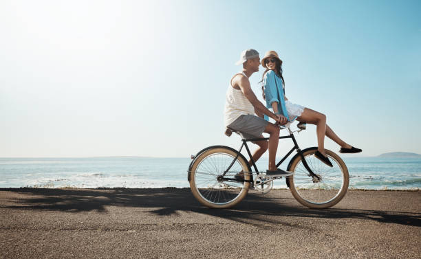 Couple riding bikes on beach boardwalk