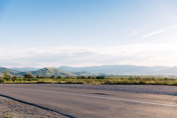 estrada de asfalto vazia com céu azul de verão e colinas no fundo. crimeia, koktebel. - road trip country road landscape street - fotografias e filmes do acervo