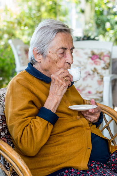 Old woman sitting and drinking Turkish coffee in the balcony on a sunny day. stock photo