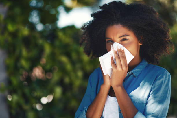 It's the season of sneezes Portrait of a young woman blowing her nose with a tissue outside hayfever stock pictures, royalty-free photos & images