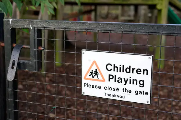 Children playing please close gate sign at play park in school child safety