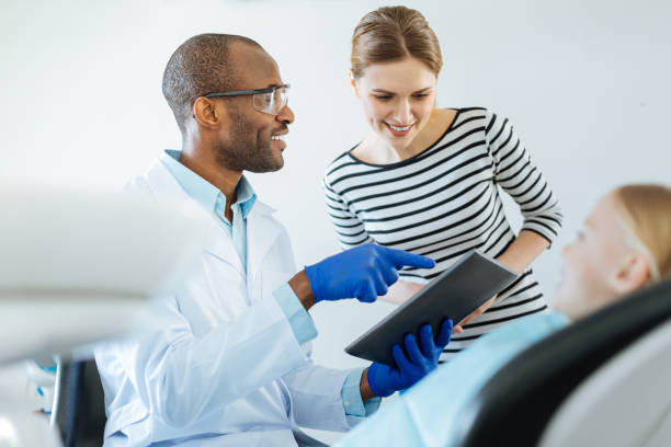 istock Charming dentist showing appointment schedule to patients mother 939035592