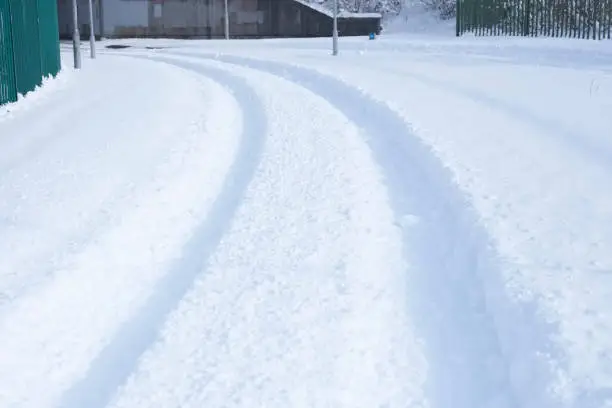 Deep white snow on road street tracks on corner bend during harsh winter cold season