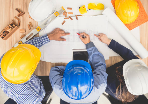 istock Group of engineers and architects discussing on table with drawing/blueprint, wearing safety helmet working for industrial construction and engineering 939036290