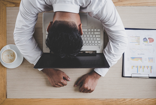 Middle age Asian businessman feeling sleepy during working on laptop and meeting at café office