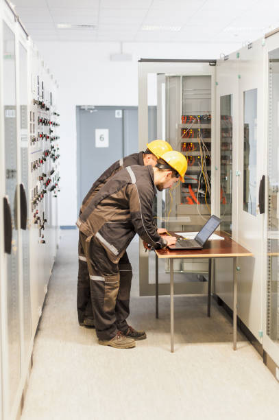 istock Two maintenance engineers inspect relay protection system with laptop comp 939039176