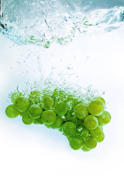 istock The fresh grape dropped into water, isolated on white background. 939040056