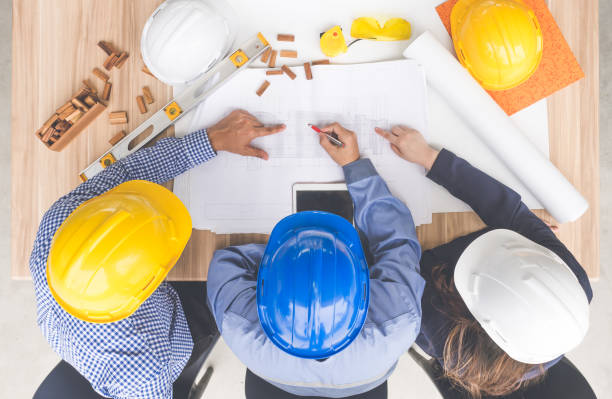 istock Group of engineers and architects discussing on table with drawing/blueprint, wearing safety helmet working for industrial construction and engineering 939043116