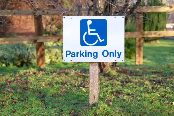Disabled parking only sign post in rural countryside car park space for special needs and elderly senior people