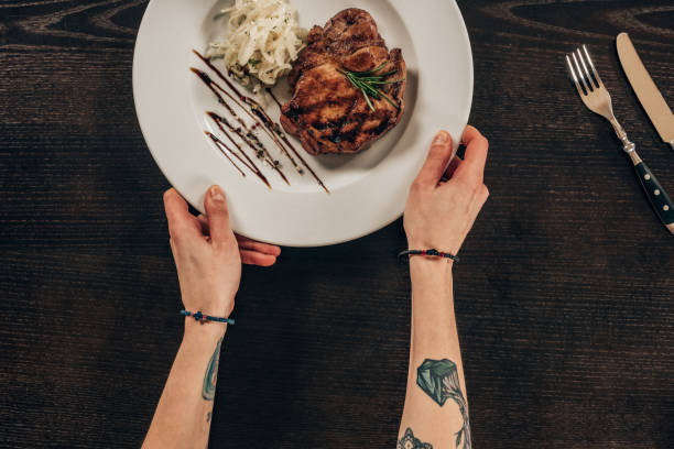 istock cropped image of woman putting plate with beef steak on table 939046530