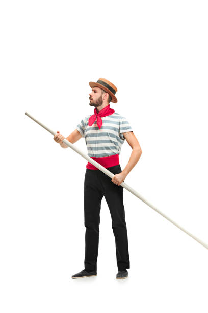 Caucasian man in traditional gondolier costume and hat Caucasian funny bearded man in traditional gondolier costume and hat with paddle standing and posing at studio isolated on white background. Serious young man looking away. Profile. Human emotions gondolier stock pictures, royalty-free photos & images