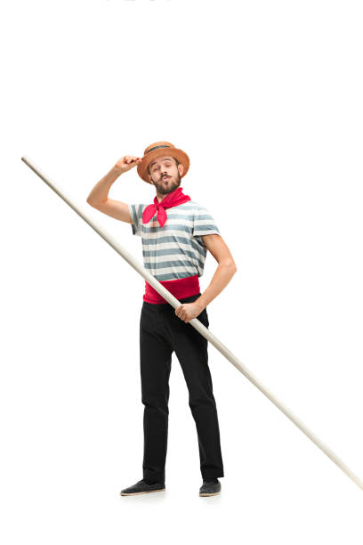 Caucasian man in traditional gondolier costume and hat Caucasian funny bearded man in traditional gondolier costume and hat with paddle standing and posing at studio isolated on white background. Smiling young man. Human emotions, facial expression concept gondolier stock pictures, royalty-free photos & images