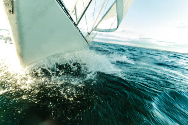 Yachting on sail boat bow stern shot splashing sea water. Sporty transportation conept.