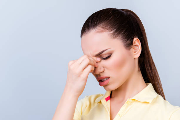 istock Bad day. Overworked stressed young brunette lady is having headache and struggling. She is wearing yellow tshirt and stands on light background 939057616