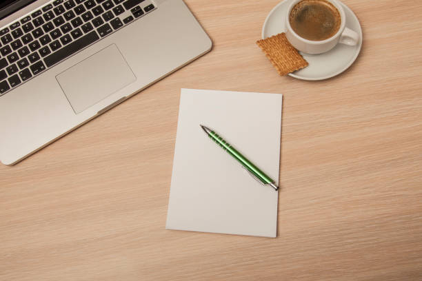 istock wooden desk with a notebook and pen, top view 939057796