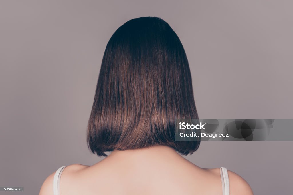 Back view of young beautiful wonam with short symmetric hair isolated on gray background Rear View Stock Photo