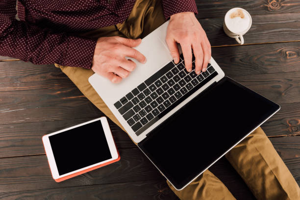 istock Businessman printing on laptop with blank screen, digital tablet and coffee cup beside 939062500