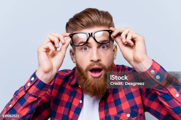 Photo libre de droit de Cest Incroyable  Bouchent Portrait De Jeune Homme Barbu Touchant Le Spectacles Et Garder Sa Bouche Ouverte Sur Fond Gris banque d'images et plus d'images libres de droit de Hommes