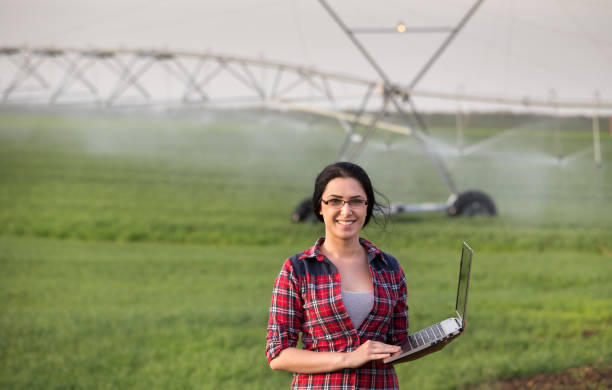 mujer del granjero con equipo de riego en campo - watering place fotografías e imágenes de stock