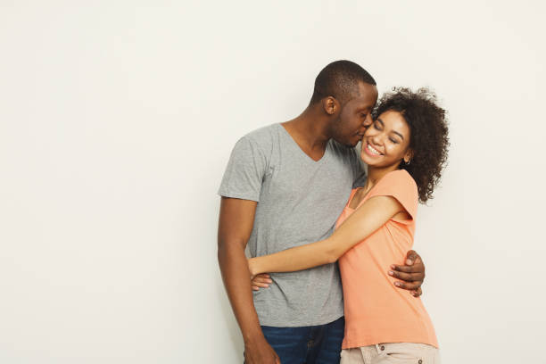 ホワイト スタジオで抱きしめる黒のカップルの笑顔 - couple indoors studio shot horizontal ストックフォトと画像