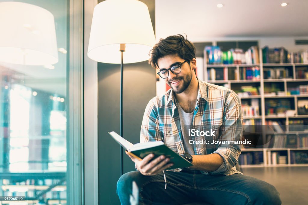 Young man reading book in the library Reading Stock Photo