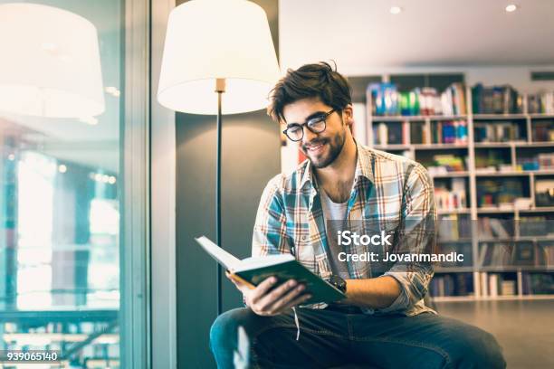 Young Man Reading Book In The Library Stock Photo - Download Image Now - Reading, Book, Men