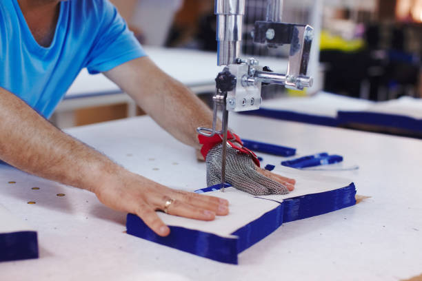 istock Cloth-cutting machine and masters hands in metal glove 939065428