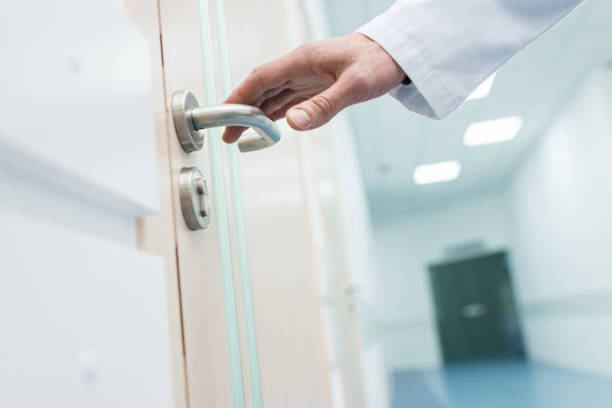 bijgesneden weergave van mannelijke arts holding deurklink in ziekenhuis - deurknop stockfoto's en -beelden