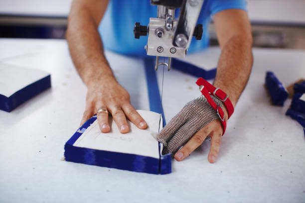 istock Cloth-cutting machine and masters hands in metal glove 939066146