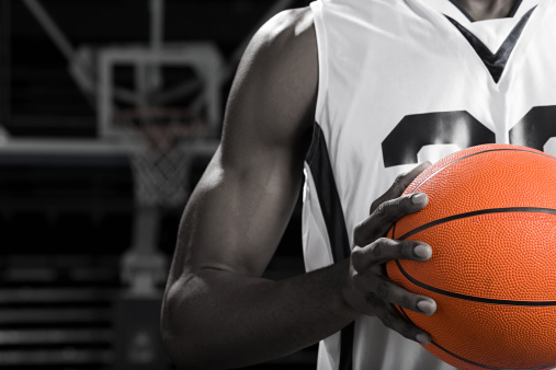 Muscular smiling African American man playing basketball, holding ball looking at camera, isolated on white background, copy space