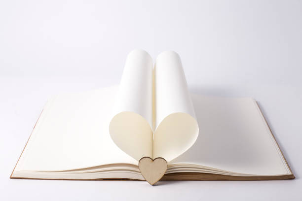 istock Openning note book white blank page with pen and lovely red ceramic heart shape on white background. 939076330