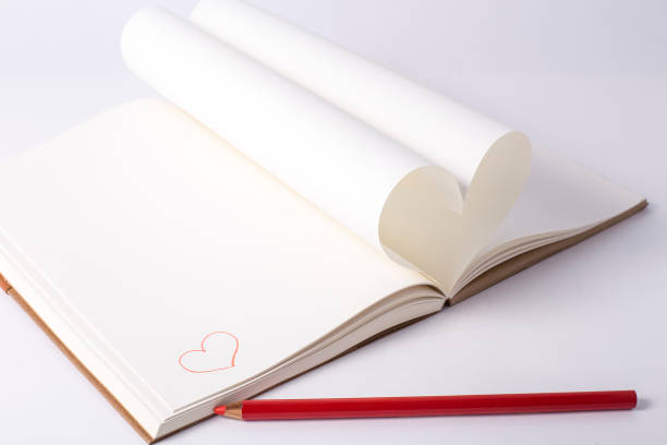 istock Openning note book white blank page with pen and lovely red ceramic heart shape on white background. 939076442