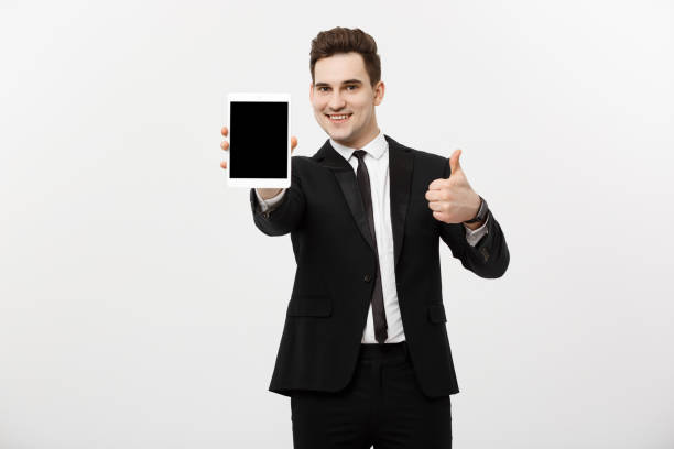 istock Business Concept: smiling businessman with tablet showing thumbs up over gray studio background 939080242