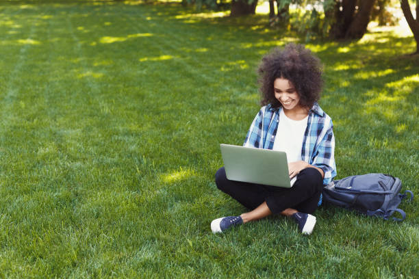 istock Happy young black woman using laptop in park 939090498