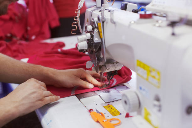 istock Textile factory workers hands sewing cloth on professional sewing machine 939091356