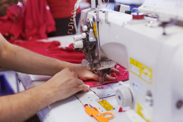 istock Textile factory workers hands sewing cloth on professional sewing machine 939098258