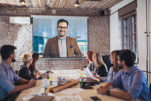 geschäftsleute, die während einer videokonferenz im büro auf projektoren schauen - conference call business meeting presentation stock-fotos und bilder