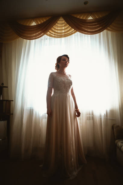 istock beautiful young bride near the window in full growth 939099084